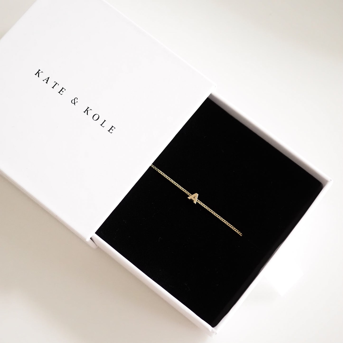 Gold initial "A" necklace in a white Kate & Kole jewellery box with a black velvet interior. Elegant luxury necklace display.