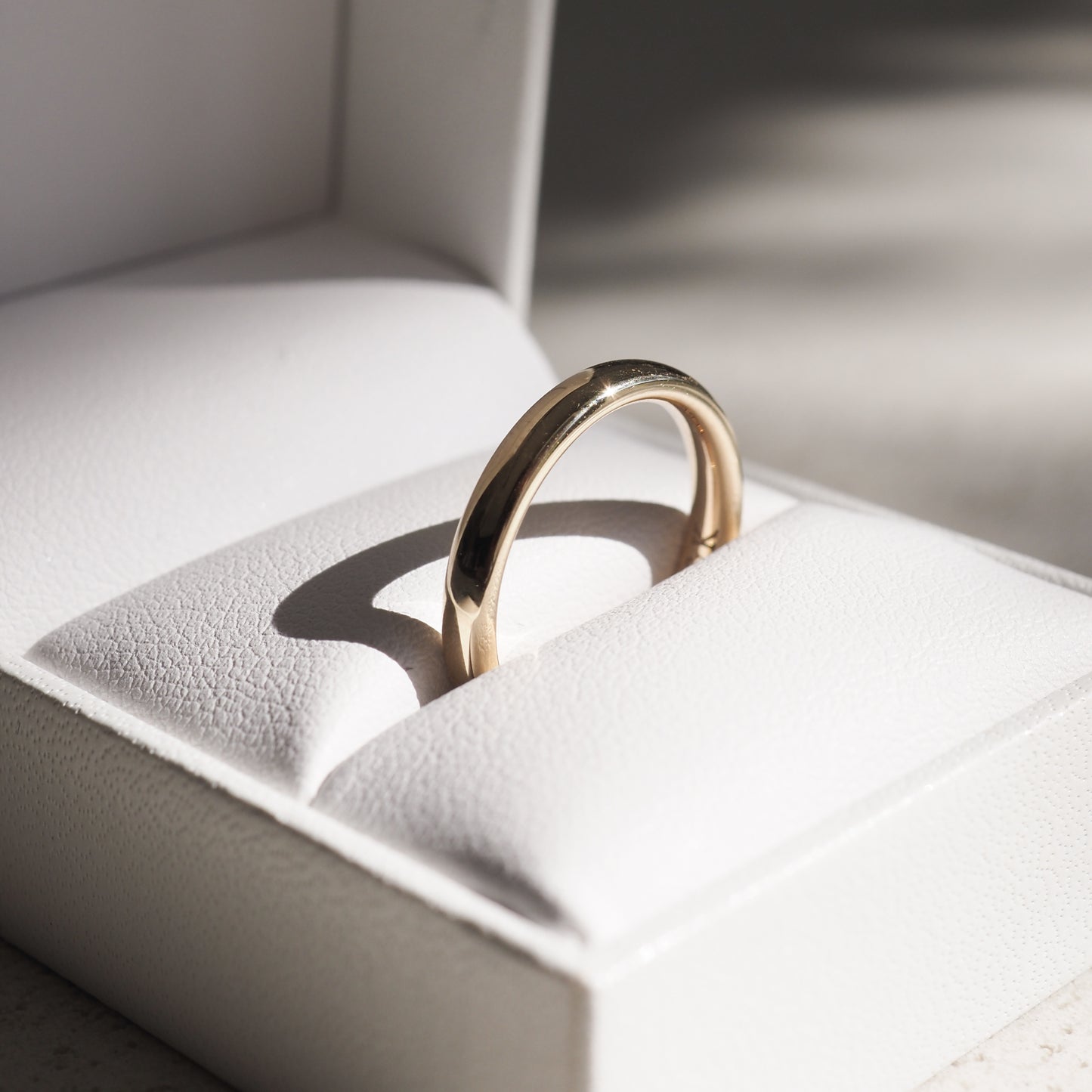 Gold ring in a white jewellery box, catching soft light, showcasing luxury and elegance. Perfect for weddings or special occasions.