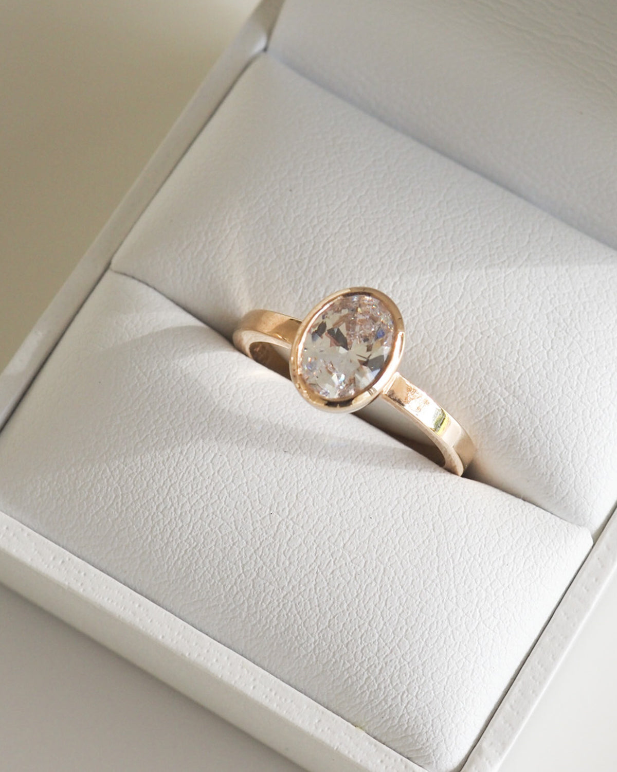 Rose gold ring with an oval diamond set in a white jewellery box, showcasing luxury design and elegance in Australian fine jewellery.