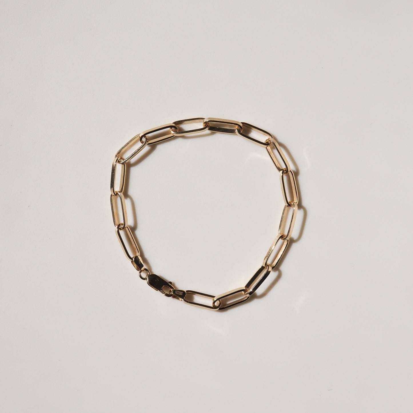 Gold link chain bracelet on a minimalist light background, showcasing luxury jewellery craftsmanship.