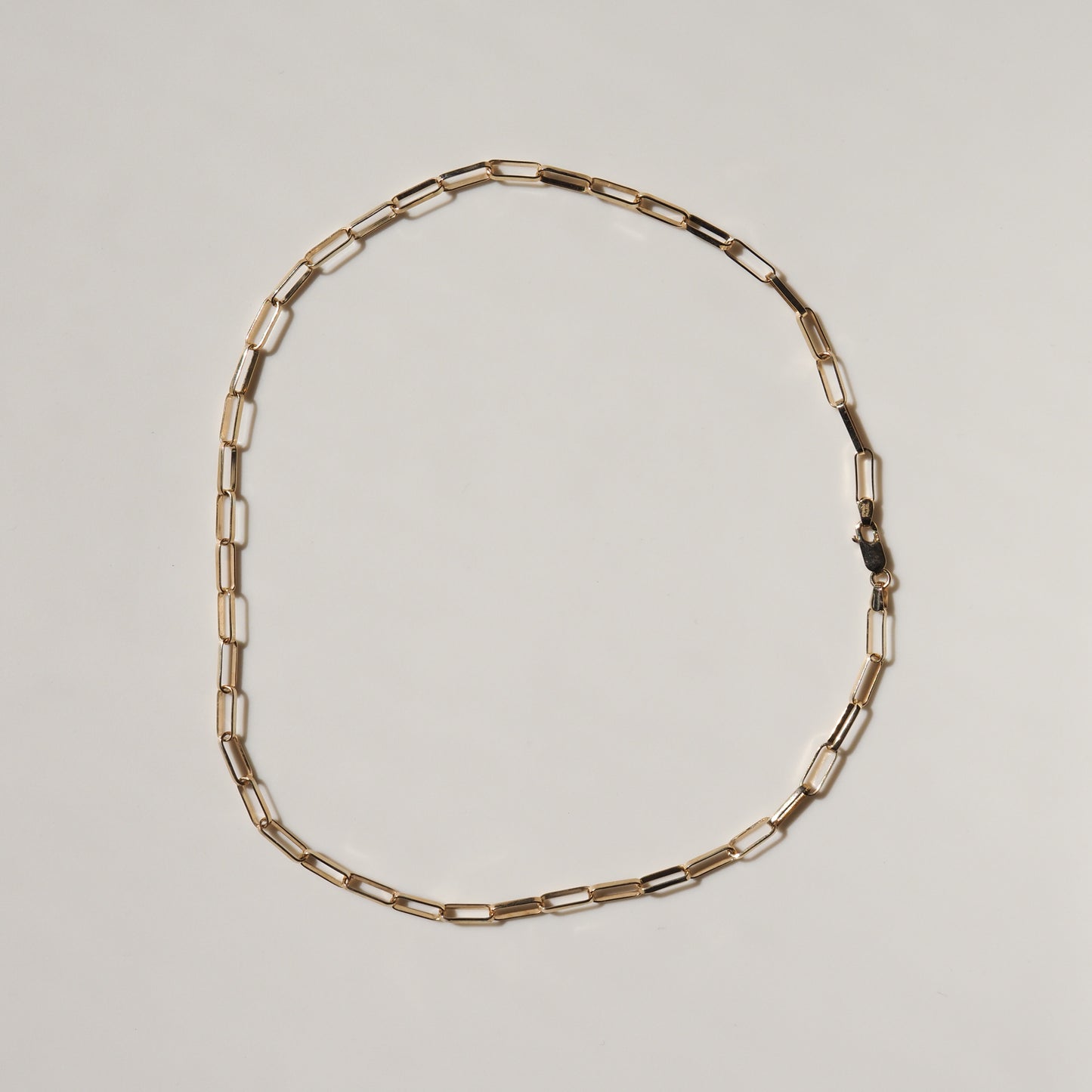 Gold link chain necklace on a plain background, showcasing luxury jewellery design with rectangular links and a clasp closure.