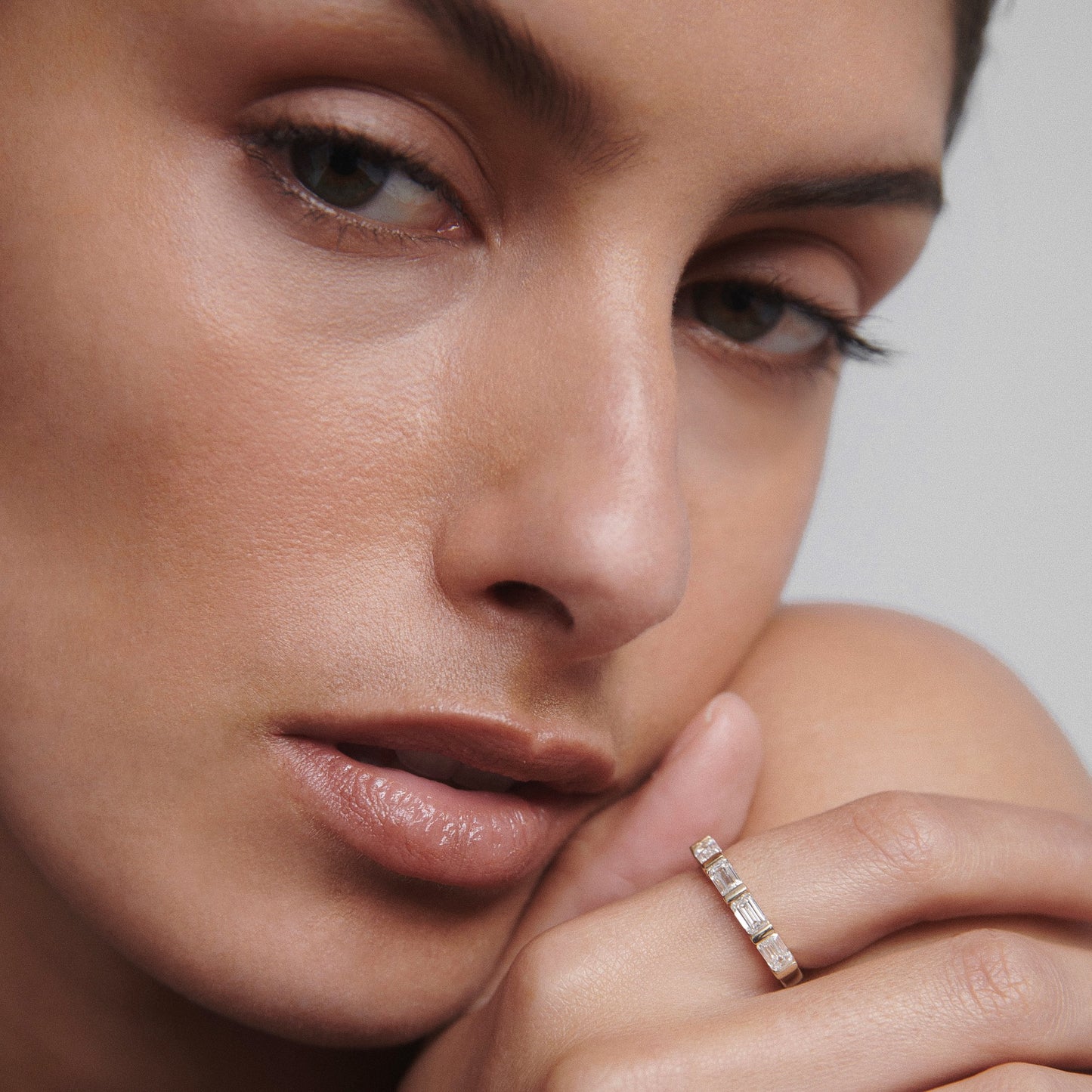 Close-up of a woman wearing a luxurious gold ring with rectangular gemstones, highlighting high-end jewellery design and elegance.
