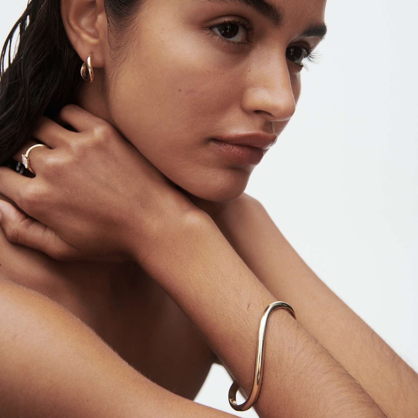Model wearing luxury gold hoop earrings, a sleek gold bracelet, and a matching ring, showcasing elegant high-end jewellery. [text overlay: Medium] 