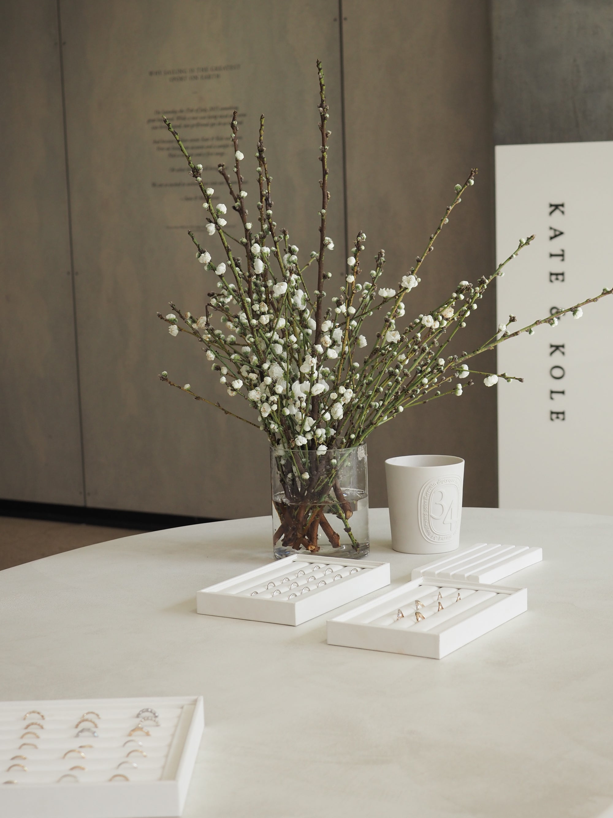 Elegant display of luxury jewellery on a sleek table, with delicate white blossoms in a vase and minimalist decor in a sophisticated setting.