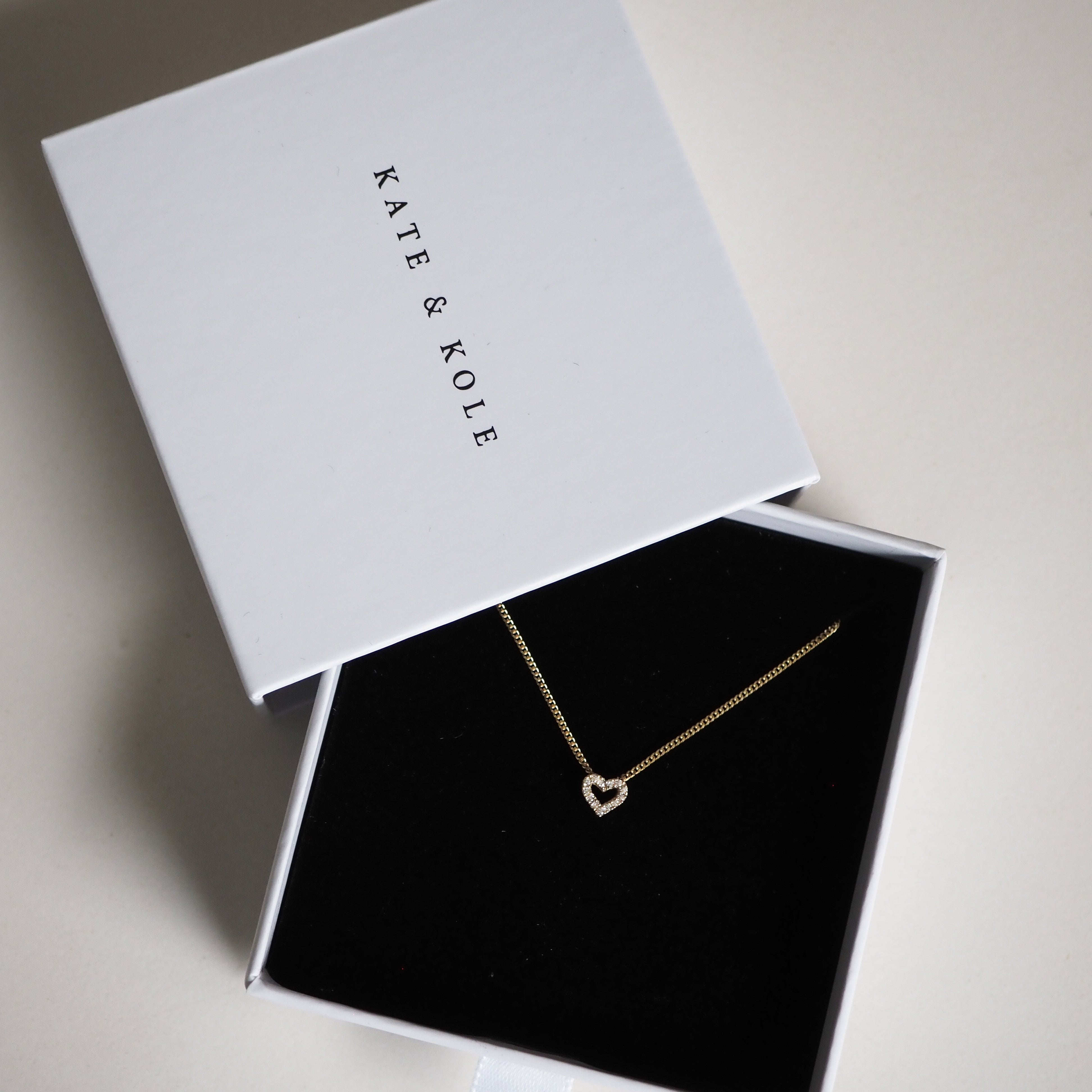 Gold heart necklace displayed in an open white Kate & Kole jewellery box with velvet lining. Perfect for luxury and elegant gift-giving.