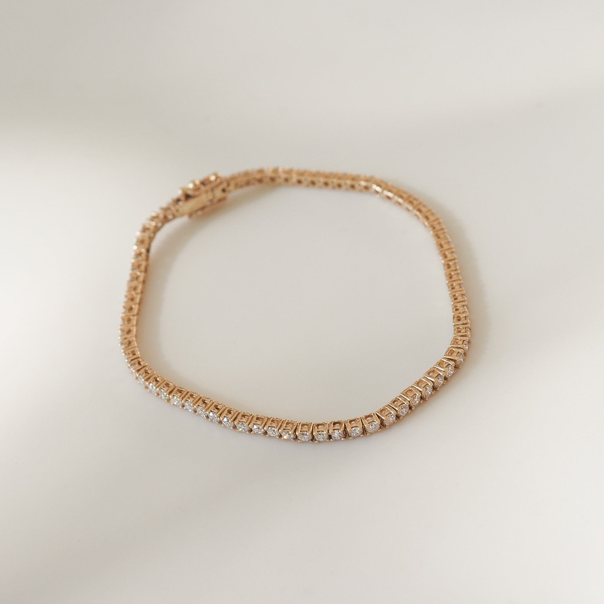 Yellow gold bracelet with clear stones on a light beige background