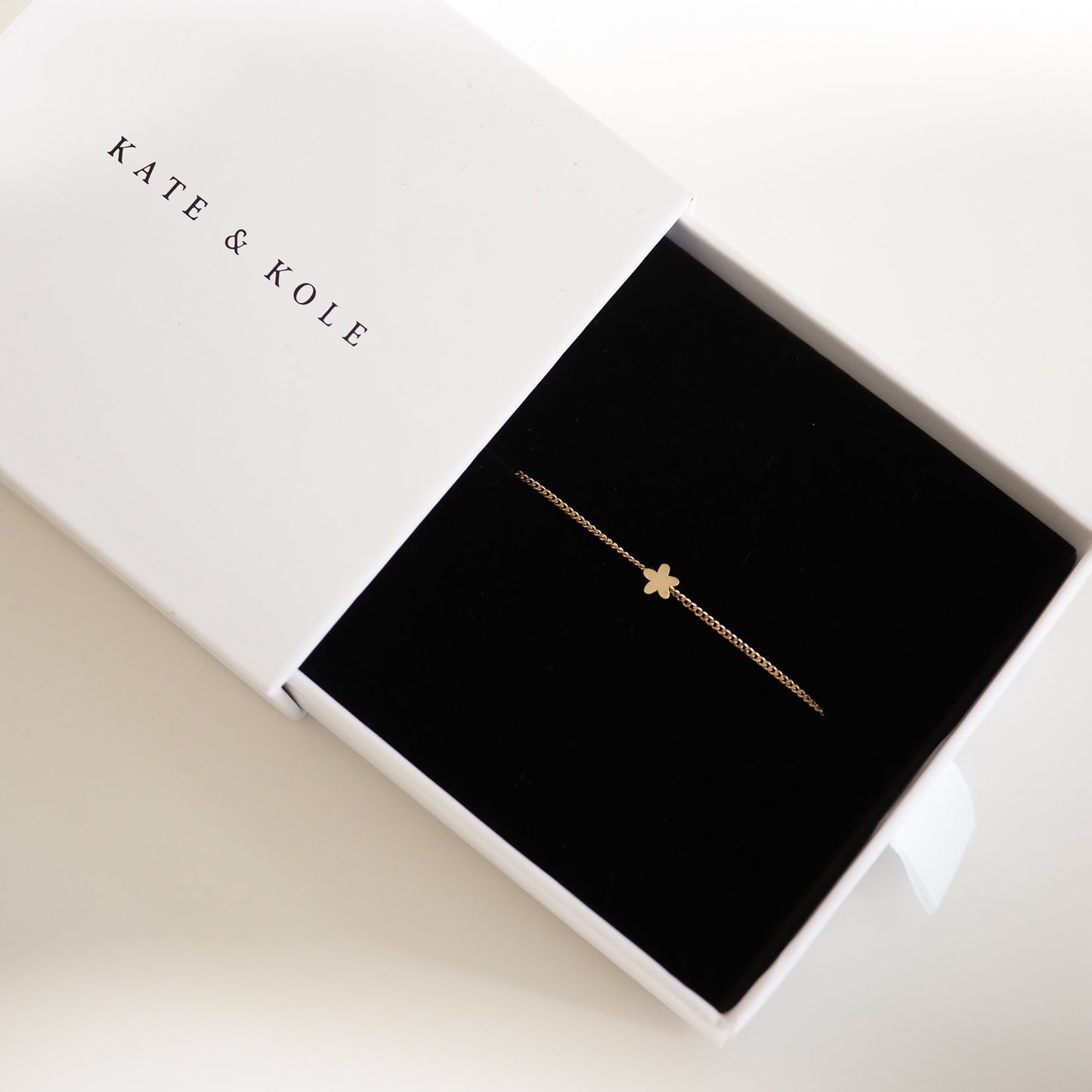 Gold clover bracelet in a Kate & Kole box. Minimalist, luxury jewellery on black velvet. Perfect gift or elegant accessory.