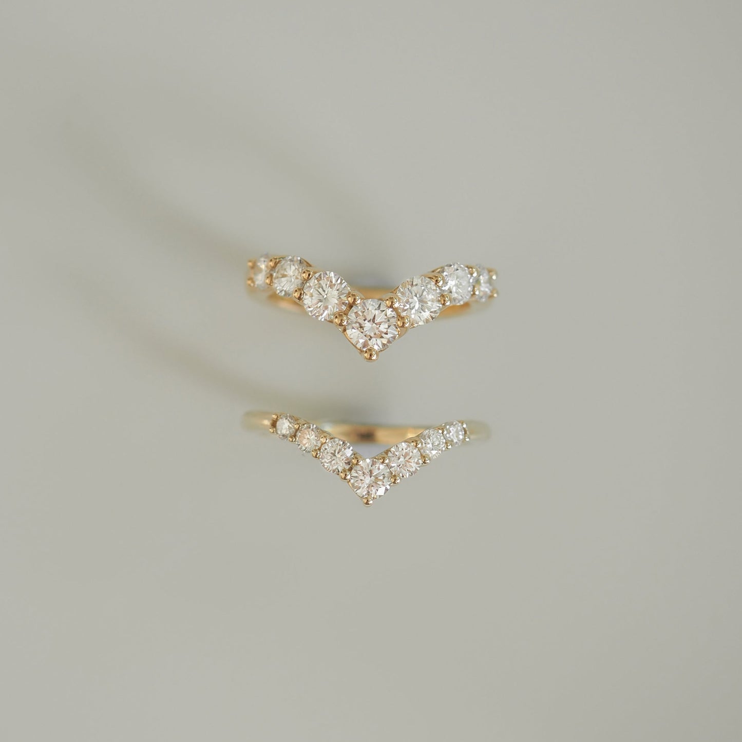 Two elegant gold chevron rings with sparkling diamonds, displayed on a soft grey background. Perfect for adding a touch of luxury.
[text overlay: Top: Bold, Bottom: Classic]