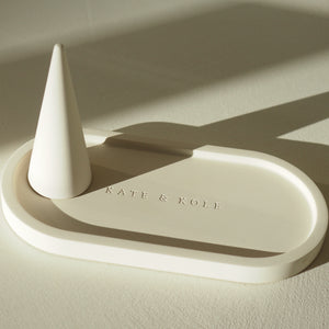 Beige ceramic tray with a ring object on a beige background, featuring 'KATE & KOLE' branding.