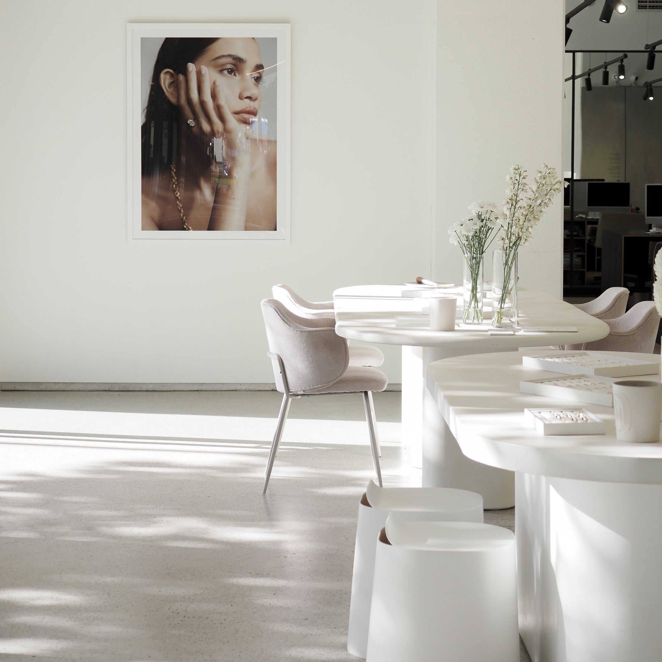 Minimalist jewellery boutique interior with soft lighting, featuring elegant seating, modern décor, and a portrait showcasing a luxury necklace.