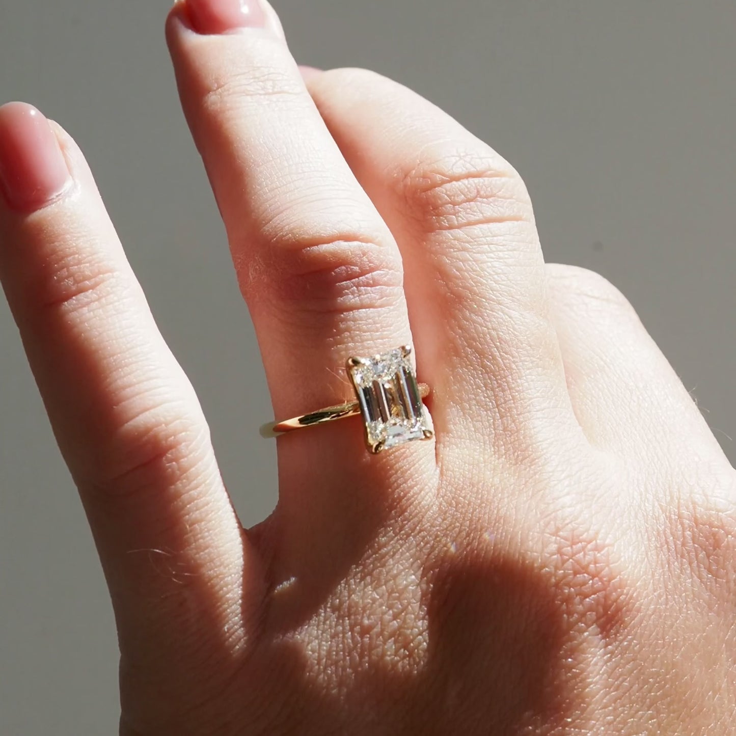 Hand wearing an emerald cut engagement ring