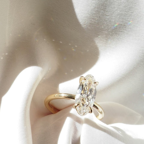 Gold ring with a Moval diamond on a light background